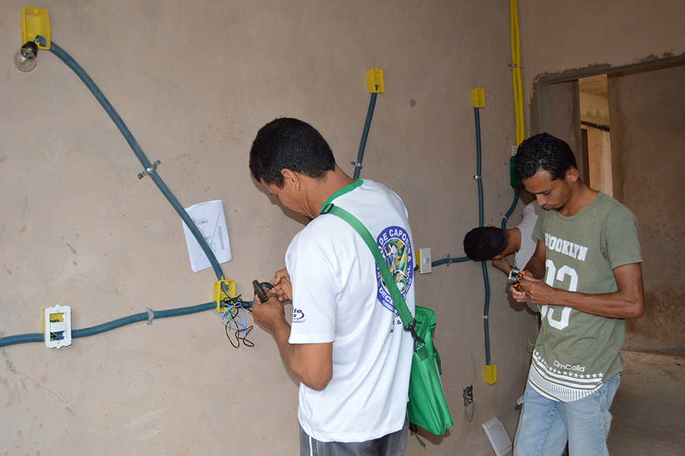 Alunos  realizando instalações de interruptores em ambiente adaptado para a aula 